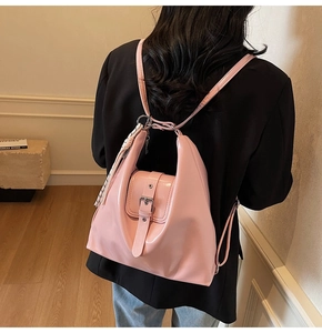 Détail d'un sac à dos en cuir verni rose avec boucle argentée et pompon tissé élégant