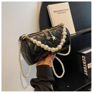 Close-up of black quilted barrel bag with pearl chains and star-shaped metal pendant
