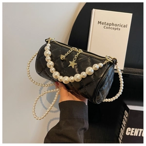 Detail of black quilted barrel bag featuring pearl handle and star-shaped gold pendant