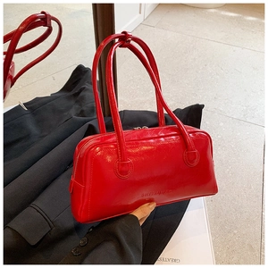 Detail of red glossy leather boston bag showing textured surface and embossed brand logo