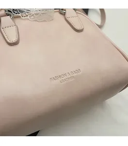 Detailed close-up of light pink PU leather handbag with lace trim and stamped lettering