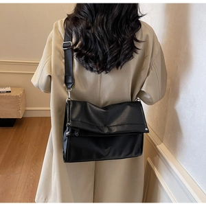Detail of black lychee grain leather crossbody bag with adjustable wide nylon strap