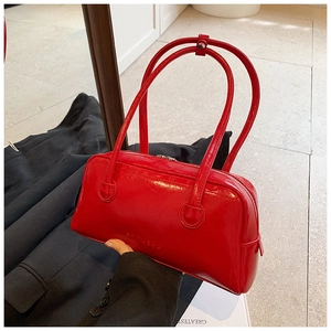 Close-up of vibrant red patent leather shoulder bag with smooth metallic zipper detail