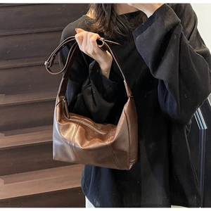 Detail of a dark brown vintage crescent leather crossbody bag with a silver zipper
