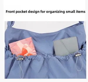 Detail of the blue nylon tote's front drawstring pocket showing organized small items