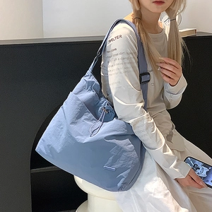 Détail du sac à bandoulière bleu brume avec cordon et texture en nylon gaufré
