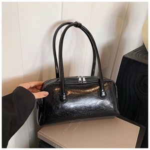 Close-up of shiny black wrinkled leather texture and silver zipper on the shoulder bag