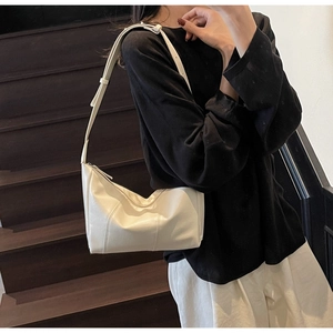 Close-up of a cream pleated crossbody dumpling bag with adjustable strap and zipper