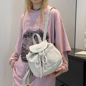 Close-up of off-white waterproof nylon backpack featuring drawstring closure and buckle details