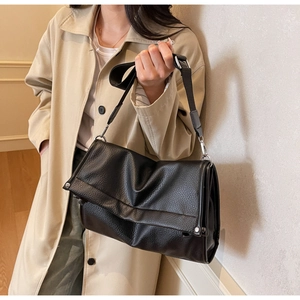 Detail of black pebbled leather tote bag showing soft folding structure and silver buckles