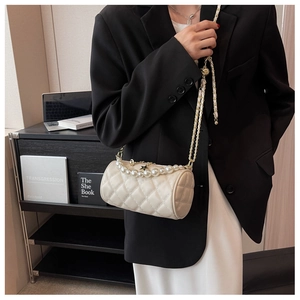 Detail of quilted cylinder bag with pearl handle and star charm worn by a model