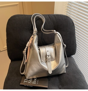 Détail du sac cabas argenté métallisé avec foulard décoratif sur un siège noir
