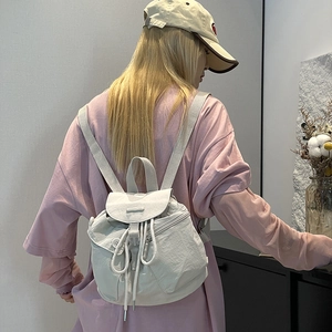 Close-up of lightweight nylon mini backpack with drawstring closure and button flap details