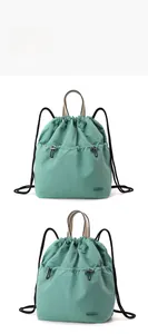 Detail view of light blue nylon drawstring backpack with front pockets and beige handle