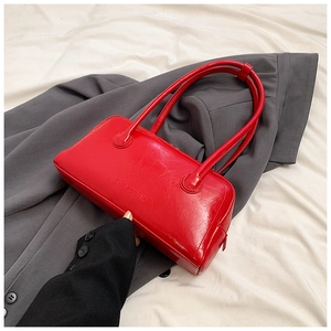 Macro view of bright red leather baguette bag with textured grain and brand logo