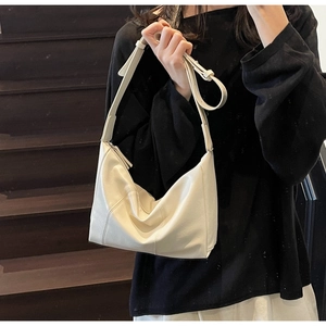 Detailed view of cream hobo bag texture and adjustable strap on a female model