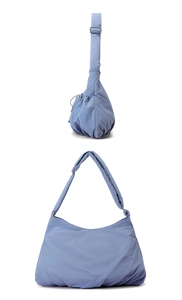 Detailed view of light blue nylon bag with pleated texture and adjustable wide shoulder strap