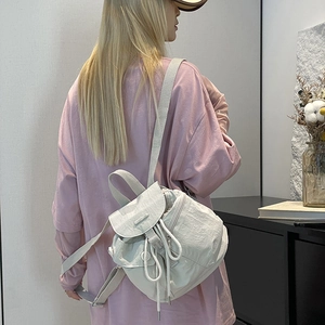 Macro detail of creamy nylon backpack featuring drawstring closure and branded logo plate