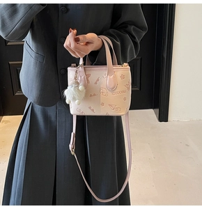 Detail of pink mini bucket bag with embossed dog motifs and white fur ball charm