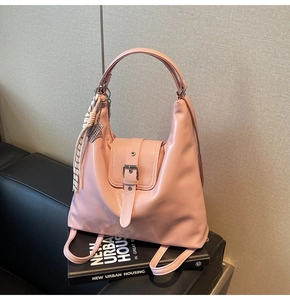 Détail d'un sac à dos en cuir rose clair avec anneau métallique et foulard décoratif