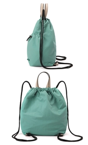 Detail of mint green nylon drawstring backpack featuring side zipper pocket and beige handles