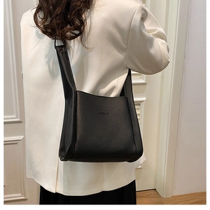 Close-up of black lychee grain leather shoulder bag with embossed UZBAG logo and texture