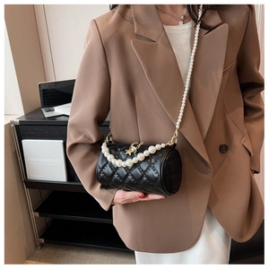 Detail of black quilted cylinder bag with pearl strap and golden star pendant