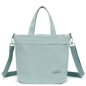Detail of mint green nylon tote showing the brand logo, texture, and adjustable strap