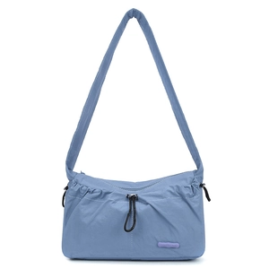 Detailed macro of a grey-blue nylon shoulder bag featuring a purple logo brand plaque