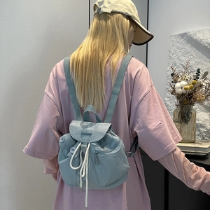 Detail view of light blue nylon backpack with drawstring closure and decorative white cord