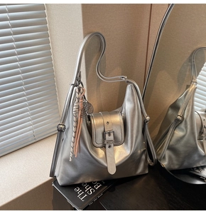 Détail d'un sac hobo argenté métallisé avec sangle à boucle et breloque à pompon