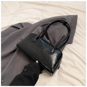 Top-down view of black glossy leather handbag with vintage crinkle texture and logo