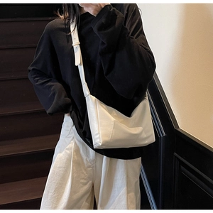 Modern white faux leather crossbody bag worn by model in a stylish indoor setting