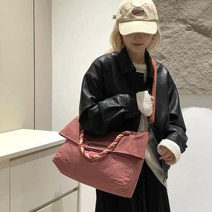 Détail du grand sac cabas en toile avec poignées tressées et bandoulière réglable sur modèle