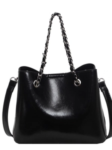 Schwarze glänzende Eimer-Handtasche aus Lackleder mit Kettenhenkel auf weißem Hintergrund