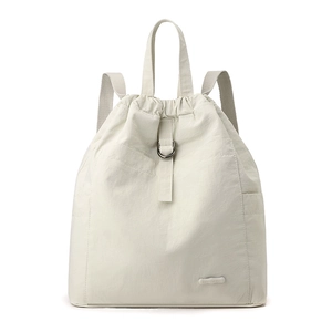 Detailansicht eines cremefarbenen Nylon-Rucksacks mit Faltenstruktur und gummiertem Markenlogo