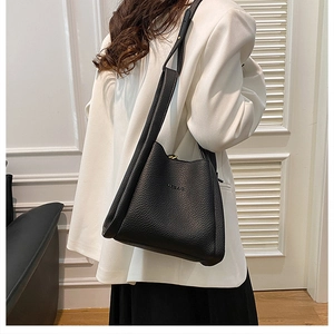 Detail of black lychee grain leather bucket bag featuring a sleek shoulder strap and logo