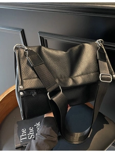 Black pebbled leather tote bag with wide nylon strap and silver metal hardware