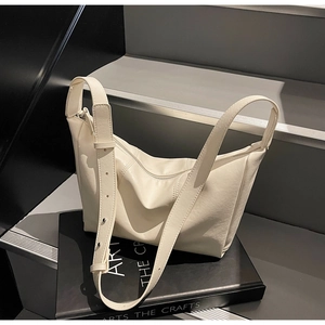 Detail of cream white leather shoulder bag featuring metal adjustment buckles and texture
