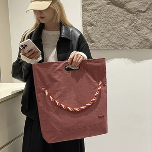 Détail du cabas en nylon rouge-brun avec corde tressée colorée et poignée découpée
