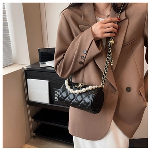Detail of black quilted cylindrical crossbody bag with pearl handle and star charm