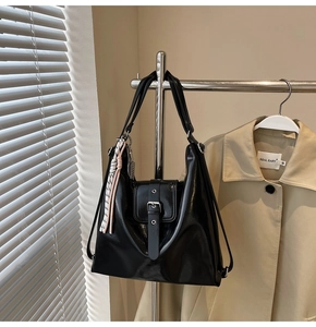 Détail du sac hobo noir brillant avec boucle argentée et pendentif tressé décoratif