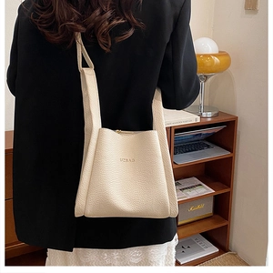 Chic beige lychee pattern leather bucket bag shown in a stylish home office setting
