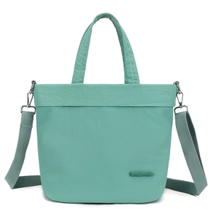Detail of light green nylon tote with adjustable shoulder strap and logo emblem
