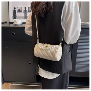 Detail of beige quilted cylindrical bag with pearl handles and star charm accessory