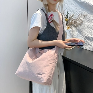 Vue détaillée du sac à bandoulière rose clair avec large sangle et fermeture à cordon