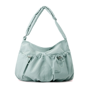 Detail of mint green pleated nylon bag featuring drawstring pockets and wide shoulder strap