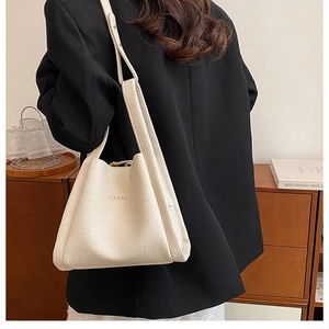 Detail of cream lychee texture bucket bag featuring embossed logo on a lifestyle model