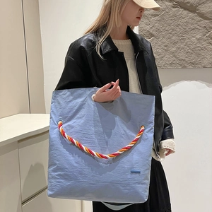 Détail du sac cabas en toile bleu clair avec anses en corde tissée tricolore