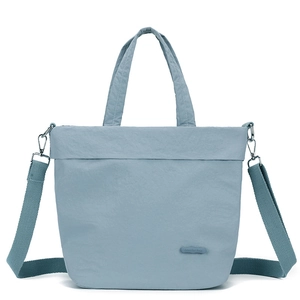 Close-up of light blue nylon tote bag with wide shoulder strap and silicone logo